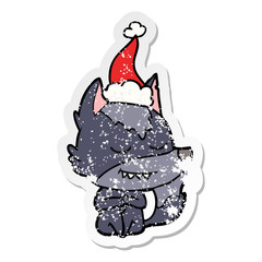 friendly distressed sticker cartoon of a wolf sitting wearing santa hat