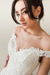 Beauty portrait of bride wearing fashion wedding dress with feathers with luxury delight make-up and hairstyle, studio indoor photo.