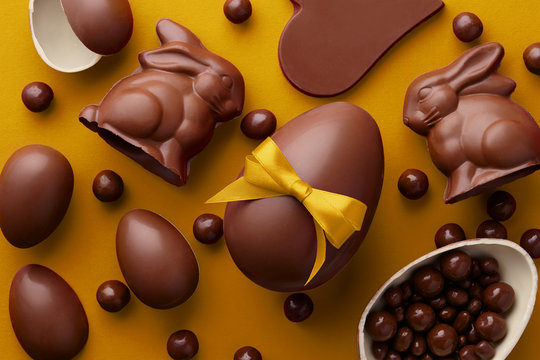 Easter composition with chocolate eggs and bunnies on yellow background, holiday concept