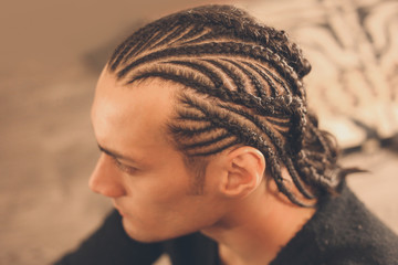 male hairstyle close-up braids, hair braided, pensive look, man portrait - obrazy, fototapety, plakaty