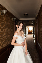 Beauty portrait of bride wearing fashion wedding dress with feathers with luxury delight make-up and hairstyle, studio indoor photo.