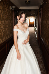 Beauty portrait of bride wearing fashion wedding dress with feathers with luxury delight make-up and hairstyle, studio indoor photo.