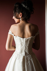 Beauty portrait of bride wearing fashion wedding dress with feathers with luxury delight make-up and hairstyle, studio indoor photo.