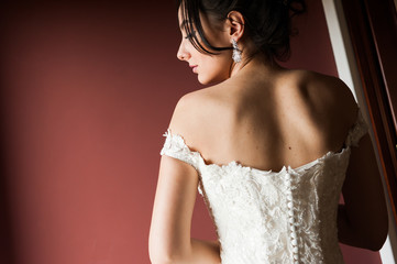 Beauty portrait of bride wearing fashion wedding dress with feathers with luxury delight make-up and hairstyle, studio indoor photo.