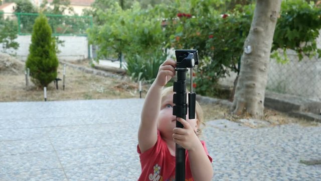 Baby playing with a monopod, kid is walking and exploring the monopod