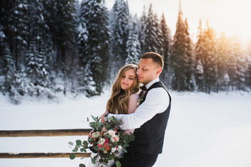 Boy and girl hug in the winter forest. A couple hugging at sunset. 