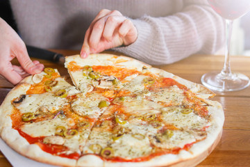 woman  takes a slice of sliced Pizza with Mozzarella cheese, Tomatoes, pepper, olive, Spices and Fresh Basil. Italian pizza. Pizza Margherita or Margarita on wooden table background