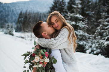 a couple hugging in the winter. boy and girl hug in the winter forest. boy and girl in the mountains