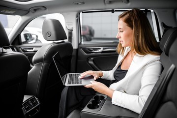 Business lady sitting in the car working on a laptop