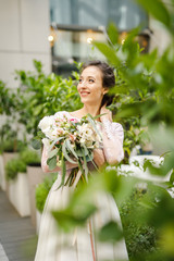 Portrait of a young beautiful wedding bride in the city near the trees