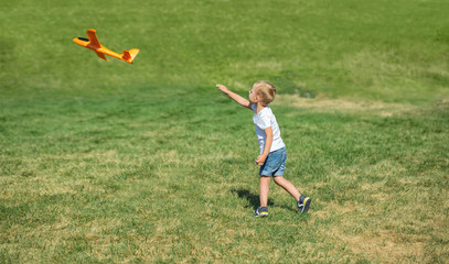 Fototapeta premium Young boy playing airplane on the meadow