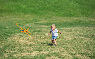 Fototapeta premium Young boy playing airplane on the meadow