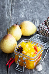 Homemade pear and chilli pepper chutney in glass jar on wooden table