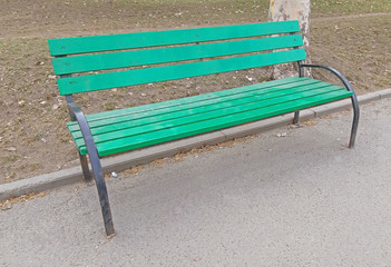 A green chair in the park on the sidewalk