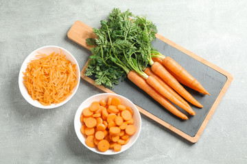 Cutting board with ripe carrots on grey table, space for text