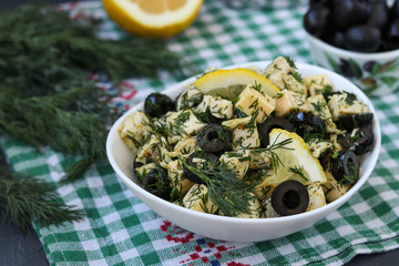 Salad with chicken, cheese and black olives in white bowls on the table