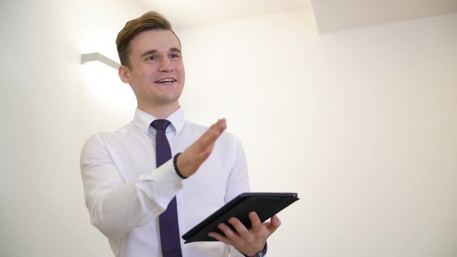 Happy young manager with the tablet. Attractive handsome manager talking and smiling while holding the tablet pc. Happy manager concept