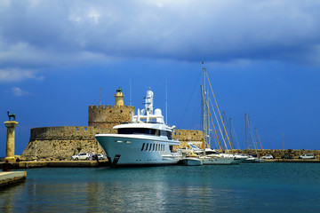 Obraz premium Beautiful port on the sea - white and yachts , medieval fortress, turquoise and blue water in Rhodes, Greece