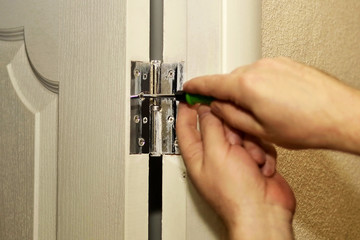 Worker installs door hinges with hand screwdriver