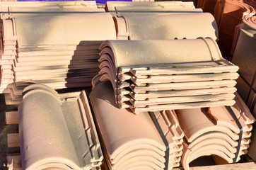 Piles of roof tiles in many rows with different number in any column. The ancient tiles are stained...
