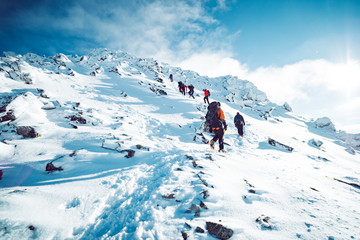 A group of climbers ascending a mountain in winter - obrazy, fototapety, plakaty