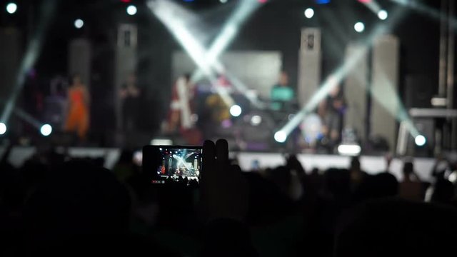 Hand Holding Record Video Camera Smartphone Live Concert Performance Taking Photo Music Band Silhouettes Dancing People Applauding Raising Hands Up Crowd Applauds Rhythm Music Musicians Perform Stage