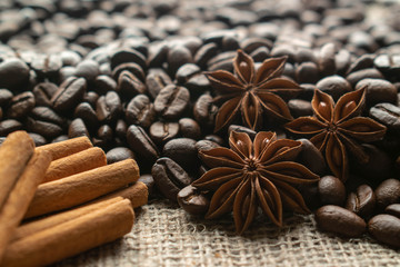 whole bean coffee with star aniseas and cinnamon sticks on light burlap