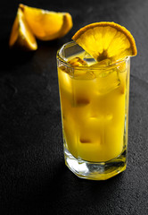 glass orange juice with ice and slices orange on black background
