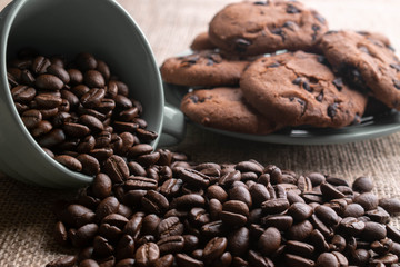 coffee beans crumbled with a cup, in the background a plate of cookies