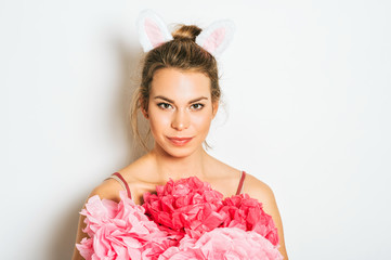 Studio shot of beautiful young woman wearing bunny ears, posing on white background, Easter concept