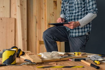 Carpenter using digital tablet in small business woodwork workshop