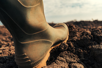 Farmer in wellington rubber boots making first step in field