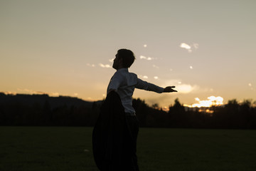 Fototapeta premium Young businessman enjoying his freedom standing in meadow