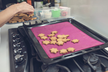 Woman taking freshly baked cookies off the hot tray