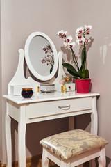 White dressing table with a mirror and a bouquet of flowers.