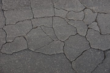 gray stone texture from old asphalt in cracks in the road