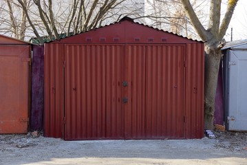 Fototapeta na wymiar large red metal garage with closed gates standing outside