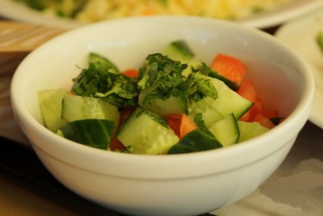 salad of green cucumbers and red tomatoes in a white plate on the table