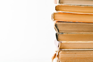 A stack of old books. Yellow frayed pages. Worn damaged book covers. Book store or e-books.