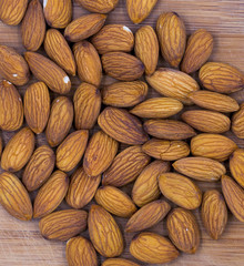 Fototapeta premium Almond nuts on timber background, top view photo. Tasty healthy snack. Scattered nuts on table
