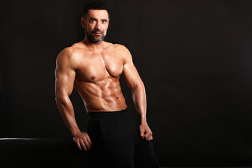 Fototapeta premium Porter of young muscular man on black background show him body , bodybuilding ,sport 