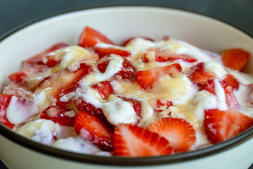 Red strawberry and white yogurt brulee. Fruit dessert on breakfast with wedges of perfectly ripe in season strawberry, closeup