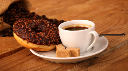 Coffee white cup, croissants on wooden table and roasted coffee beans. Breakfast concept