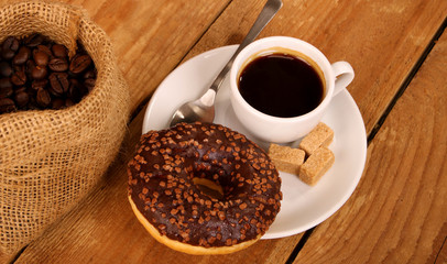 Coffee white cup, croissants on wooden table and roasted coffee beans. Breakfast concept