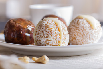 Energy balls cakes with chocolate  caramel and coconut on white plate on linen napkin.