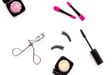 decorative cosmetic set with lash curler and mascara on white woman desk background top view