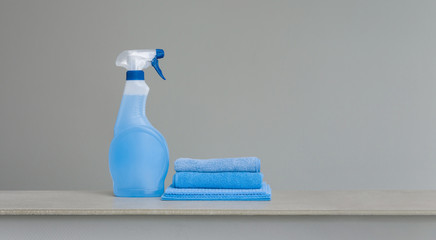 Cleaning blue spray bottle with plastic dispenser and cloth for dust  on grey background. Cleaning tools. Copy space.