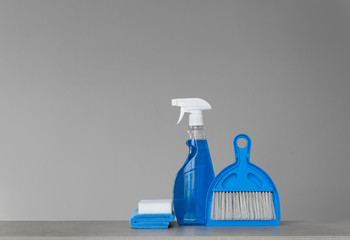 Blue cleaning kit on neutral background: Spray detergent, dust cloths, sponge, scoop and broom. Copy space.
