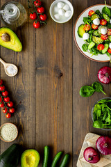 Obraz na płótnie Canvas Cooking fresh salad. Vegetables, greens, spices, plate of salad on dark wooden kitchen desk top view copy space frame