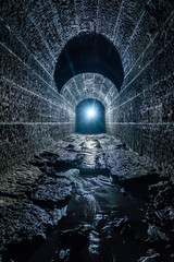 Old vaulted flooded round underground drainage sewer tunnel with dirty sewage water